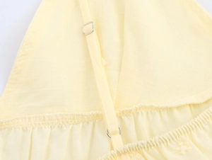 Detail of adjustable shoulder strap and embroidery on yellow cotton poplin top