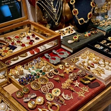 Collection of vintage gold earrings and necklaces with colorful gems on antique books