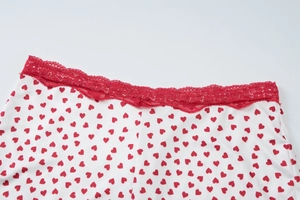 Détail de la dentelle rouge et de l'imprimé cœur sur coton blanc avec un petit nœud