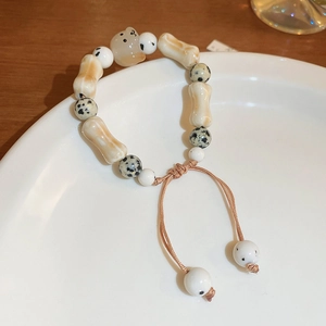 Macro detail of bodhi bead bracelet featuring cartoon puppy pendant and braided cord