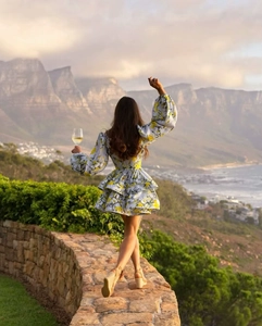 Floral puff sleeve dress with tiered skirt shown against a scenic coastal mountain view