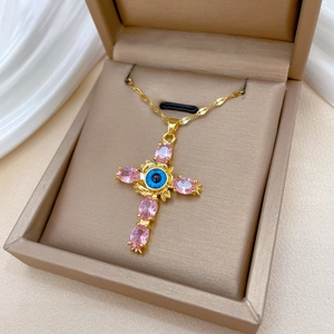 Golden titanium steel cross necklace with blue evil eye and pink gems in jewelry box
