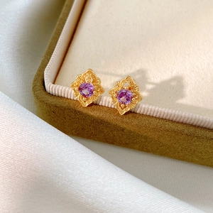 Detailed close-up of vintage gold rhombic earrings with purple zircon and intricate carving