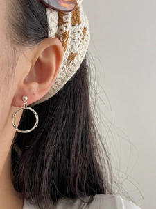 Close-up of geometric silver hoop earrings with tassels on a model for a minimal look