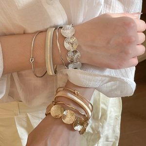 Detail view of stacked irregular metal bangles showing hammered texture and smooth finish