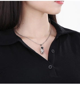 Close-up of a silver astronaut pendant on a fine chain necklace worn by a model