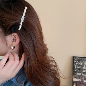 Detailed view of silver hair clip with rhinestone letter design on female model