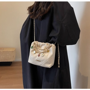 Close-up of white quilted bucket bag with golden chain and colorful heart charms