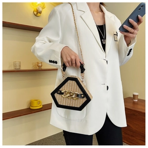 Detail of hexagonal straw handbag with gold chain accent and black leather trim