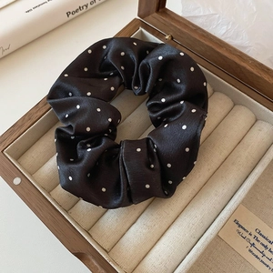 Gros plan du chouchou en satin à pois noirs et blancs dans une boîte à bijoux en bois