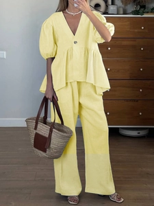 Detail of yellow linen two-piece set featuring V-neck puff sleeve top and wide-leg trousers