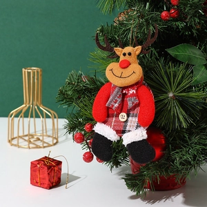 Close-up of a plush reindeer Christmas ornament hanging on a festive tree branch