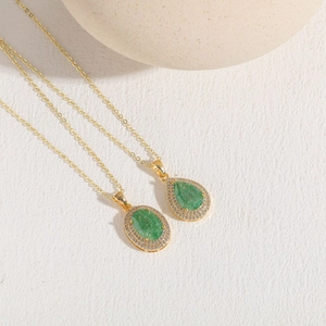 Close-up of gold plated teardrop and oval emerald zircon pendants on elegant chains