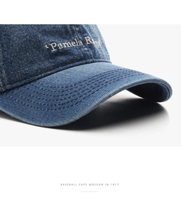Detail of dark blue denim baseball cap with white embroidery and stitched brim