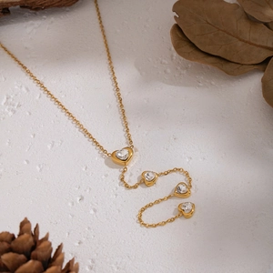 Close-up of golden necklace featuring interconnected heart pendants with clear gemstones
