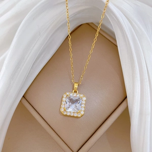 Close-up of gold cubic zirconia square pendant necklace on a beige jewelry box