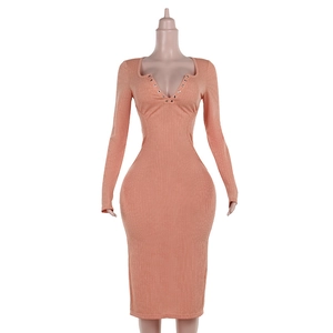 Dettaglio dell'abito in maglia rosa con scollo a V profondo e occhielli metallici decorativi