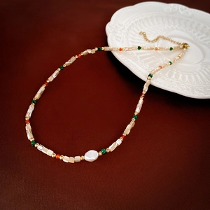 Baroque pearl beaded necklace with shell beads and vintage gold chain on red background