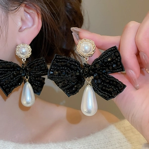 Detail of beaded bow earrings with water drop pearl pendant shown on model