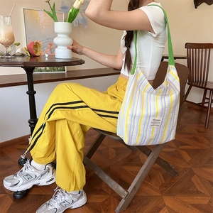 Détail du sac fourre-tout rayé en toile avec large bandoulière verte et étiquette tissée