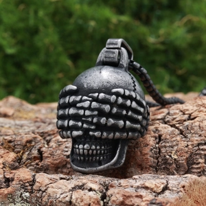 Gothic vintage silver skull pendant necklace with hands over eyes on a tree bark