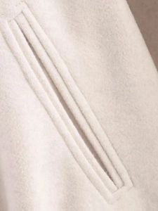 Détail macro de la poche passepoilée sur un blouson aviateur en laine blanc cassé