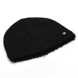 Detail of black knit beanie featuring fuzzy wool texture and gold rose metal emblem