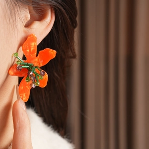 Close-up of orange vintage resin flower earring with colorful beads on a female model