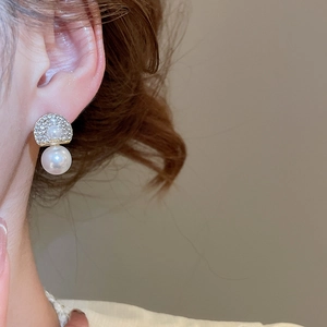 Close-up of elegant double pearl drop earrings with sparkling rhinestones on model