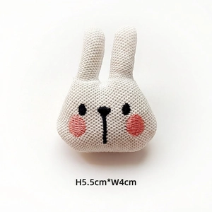 Detail of knitted bunny plush head accessory with embroidery measuring 5.5cm by 4cm
