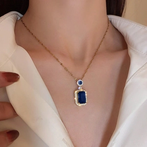 Detail of a vintage gold necklace featuring a rectangle blue gemstone pendant with diamonds