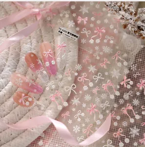 Close-up of 3D embossed nail stickers featuring white snowflakes and pink bows