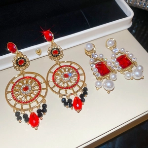 Détail de boucles d'oreilles de luxe avec strass, perles et cristaux rouges sur coffret
