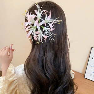 Detail of red Lycoris hair clip with gradient petals worn on dark hair back view