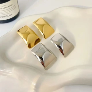 Minimalist square geometric earrings in gold and silver finish on a white tray