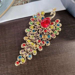 Close-up of a peacock brooch with colorful rhinestones on a rustic wooden background