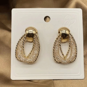 Close-up of golden mesh texture and twisted rope detail on interlocking teardrop earrings