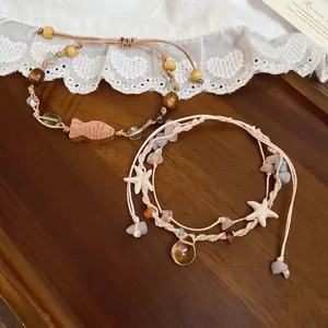 Handgefertigtes Seestern-Armband mit Natursteinen und Holzfisch auf Holzgrundhintergrund
