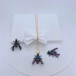 Detailed close-up of bee pendant with colorful zircon stones on gold chain jewelry