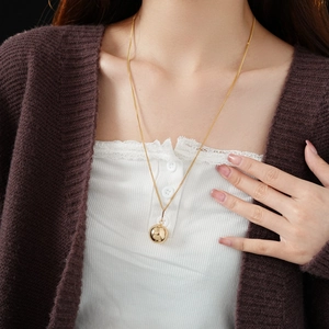 Close-up of a minimalist golden ball pendant necklace worn on a female model