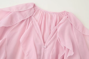 Close-up of pink chiffon blouse neckline featuring ruffled layers and button detail