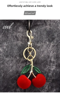 Close-up of red flocked cherry keychain with green glitter leaves and gold metal hook
