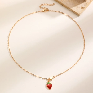 Dettaglio della collana dorata con ciondolo a fragola rossa e piccolo cuore dorato