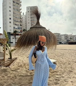 Detail eines hellblauen Häkelkleides mit V-Ausschnitt und Glockenärmeln für den Strand