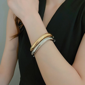 Macro view of polished gold and silver minimalist bangles styled on a wrist