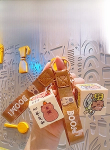 Close-up of Kapibara cube keychain with woven strap and rotating mini cube charms