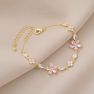 Elegant gold bracelet featuring pink zircon petals and white marquise stones on beige fabric