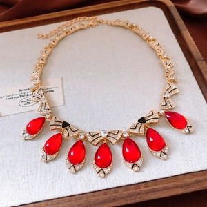 Detail of vintage gold necklace featuring red teardrop gemstones and clear rhinestones