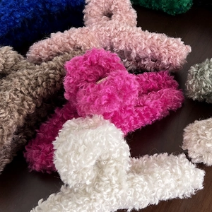 Close-up of plush teddy fleece claw clips in multiple vibrant colors on dark background