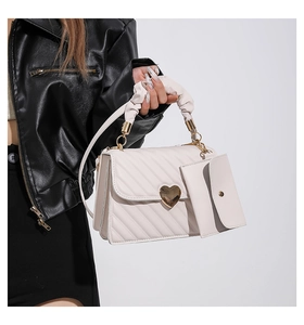 Detail of white quilted crossbody bag with golden heart lock and small coin purse